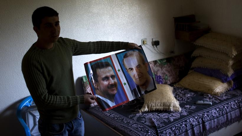 Syria: A man holds a picture of Syrias President Bashar al-Assad and his father Vater Hafez al-Assad (2010).