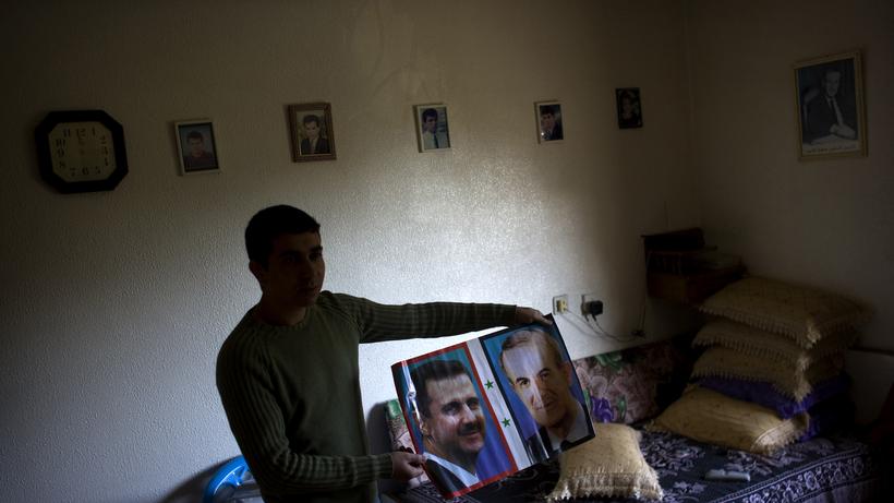 Syria: A man holds a picture of Syrias President Bashar al-Assad and his father Vater Hafez al-Assad (2010).