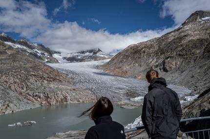 Schweiz: Tourists watch the Rhone Glacier and its glacial lake due to the melting of the glacier, above Gletsch, on September 30, 2024. A snowy winter provided no respite for Switzerland's glaciers, which shed 2.4 percent of their volume over the past year, with sand blown in from the Sahara accelerating the summer melt. The past 12 months have been "exceptional both in terms of accumulation and melt" for the Swiss glaciers, a fresh study from Glacier Monitoring in Switzerland (GLAMOS) showed on October 1, 2024. (Photo by Fabrice COFFRINI / AFP) (Photo by FABRICE COFFRINI/AFP via Getty Images)