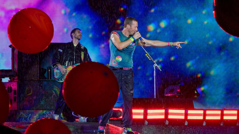  Chris Martin, Sänger der britischen Band Coldplay steht bei einem Konzert im Rahmen der "Music of the Spheres Tour 2024" bei strömendem Regen in der Merkur auf der Bühne.