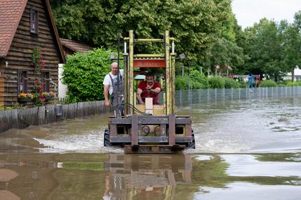 Ehrenamtliche Helfer: Helfer fahren mit einem Gabelstapler über eine überflutete Straße im Ortskern. (zu dpa: «Hochwasser in Bayern: Besuch aus Berlin und Bangen um Vermisste») +++ dpa-Bildfunk +++