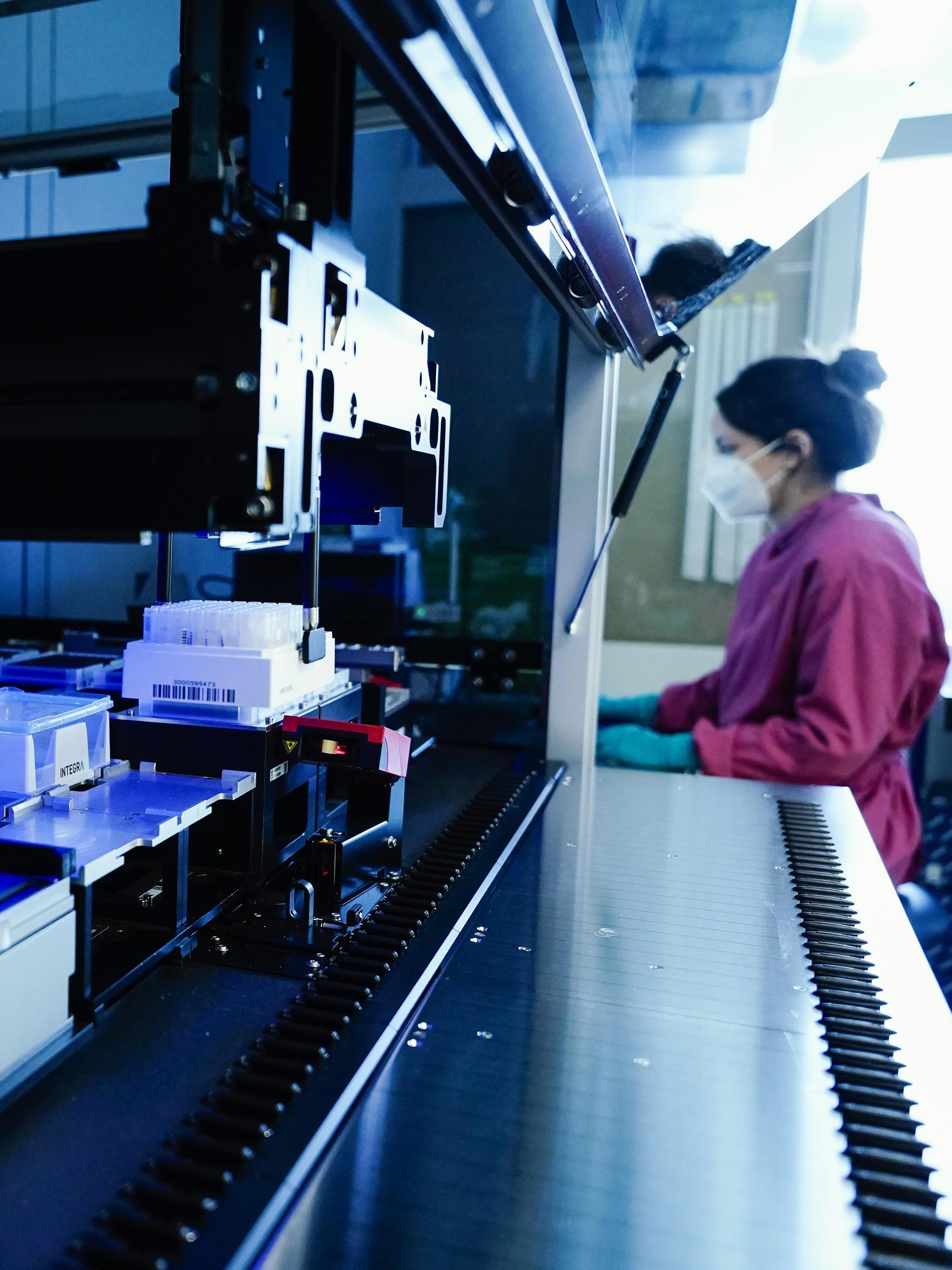 Science Temporary Contract Law: An employee at the Center for Molecular Biology at the University of Heidelberg stands behind a sampling robot that cleans RNA from throat rinse solutions.