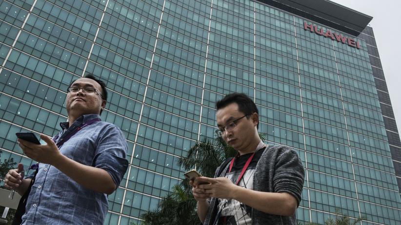 Google und Huawei: Huawei-Mitarbeiter schauen auf ihr Smartphone nahe der Firmenzentrale des Unternehmens im chinesischen Shenzhen. 