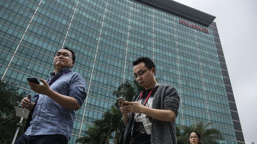 Google und Huawei: Huawei-Mitarbeiter schauen auf ihr Smartphone nahe der Firmenzentrale des Unternehmens im chinesischen Shenzhen. 