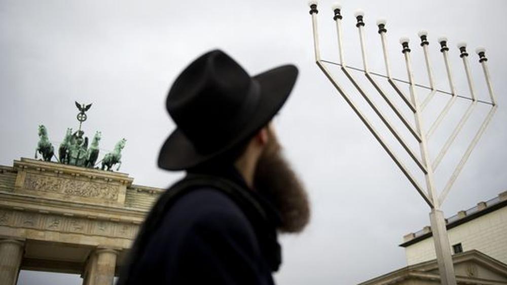 Expertenbericht: Ein Rabbiner am Brandenburger Tor in Berlin während der Feiern zum jüdischen Chanukka-Fest im Dezember