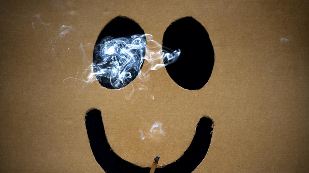 Drogenpolitik: Ein Mann raucht versteckt in einem Karton Marihuana.