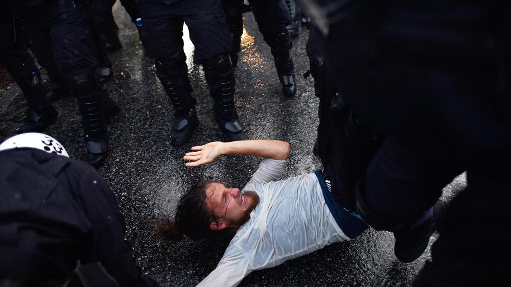 Polizei Hamburg: Berechtigter Einsatz? Ein Demonstrant wird von Polizistin in Hamburg überwältigt.