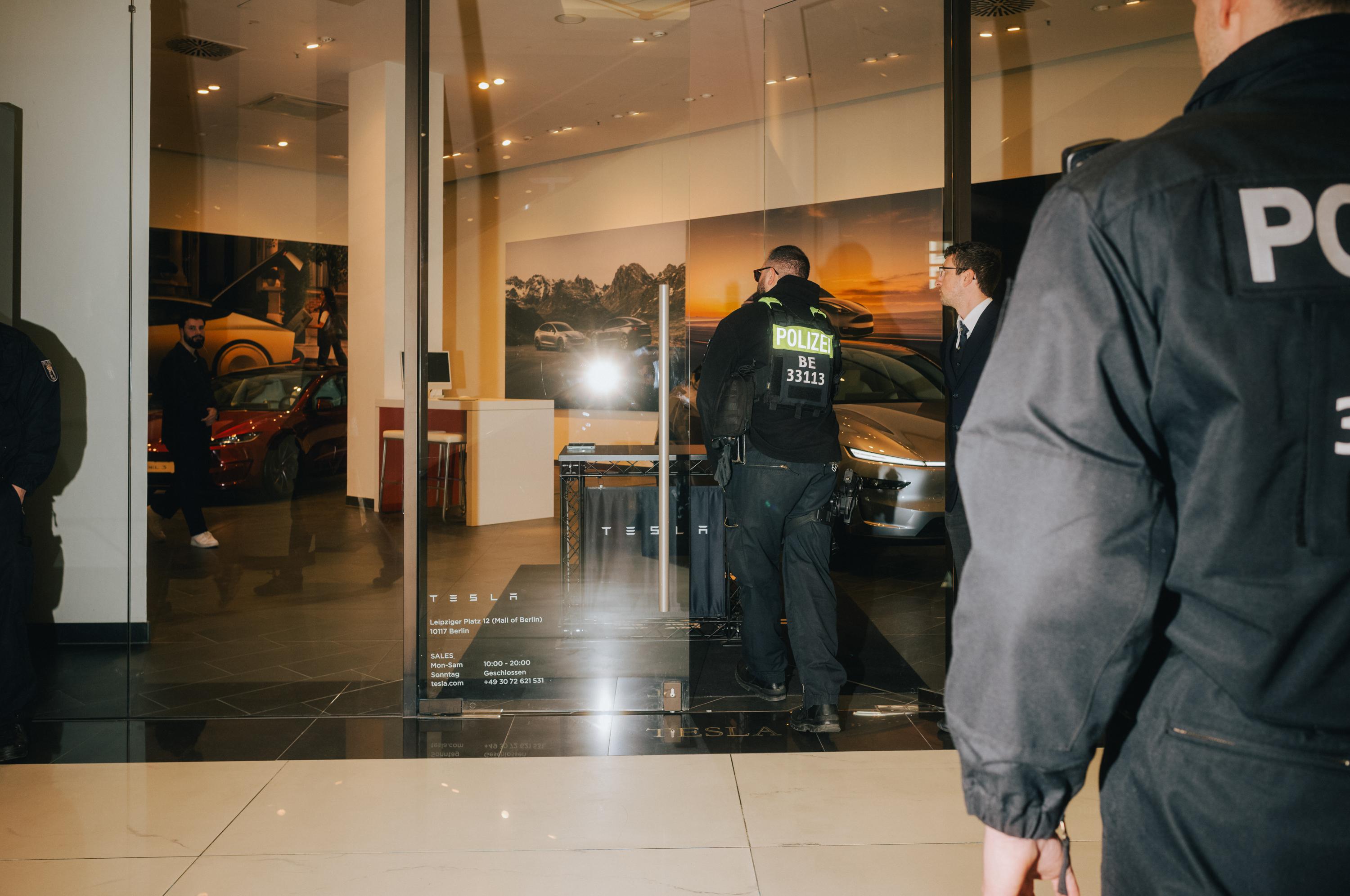 Police protect a Tesla shop during protests against Elon Musk.