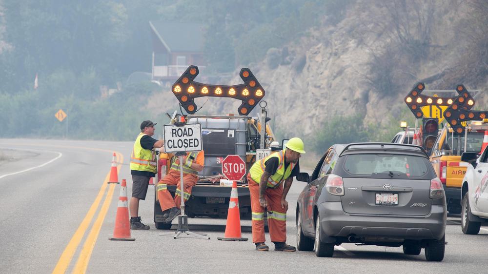 Waldbrände: Rettungskräfte sprechen an einer wegen der Waldbrände gesperrten Stelle des Highway 97 südlich von Peachland mit dem Fahrer eines Autos.