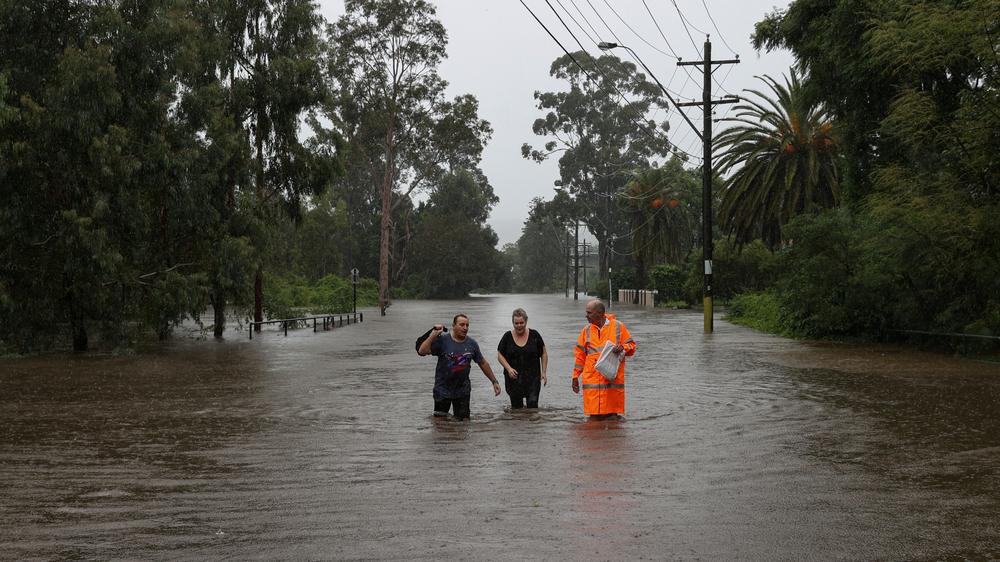Ostküste: Anwohnende waten auf einer Wohnstraße in Sydney durch Hochwasser.