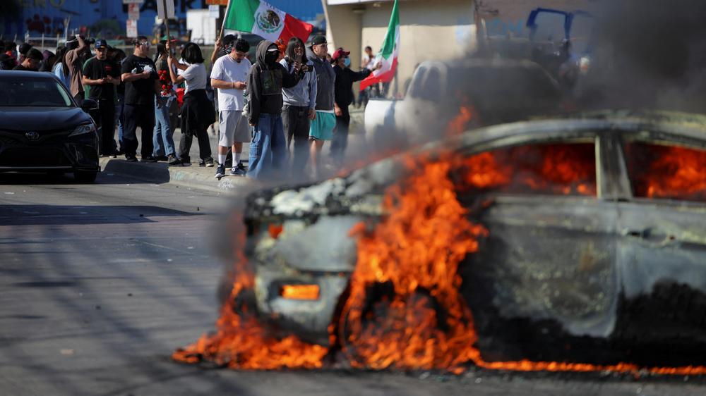  Ein Auto gerät bei einer Demonstration gegen Migrantenfestnahmen in Los Angeles in Brand.