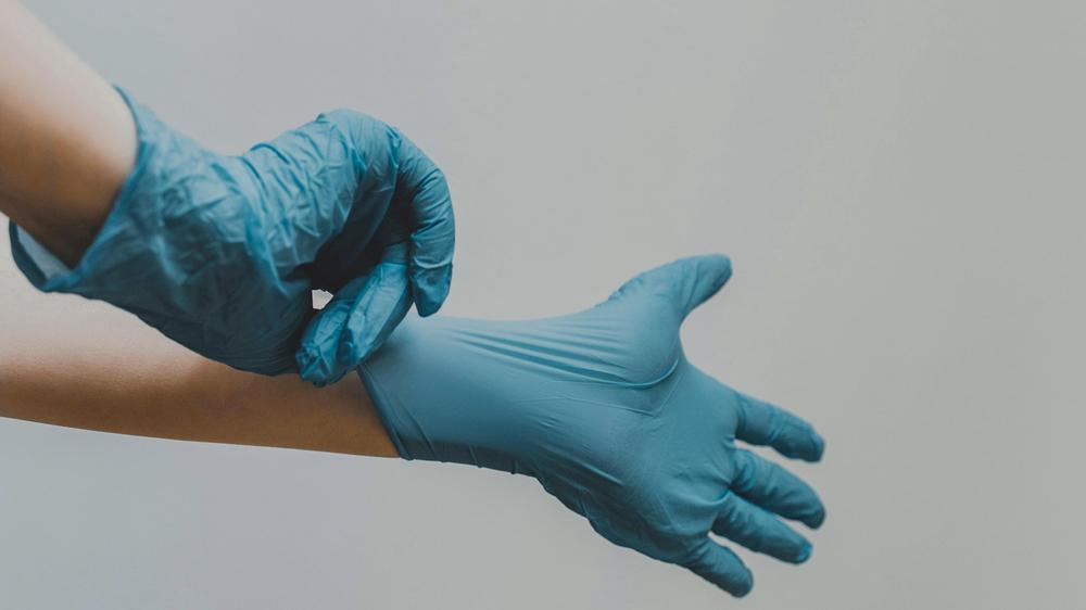 Geschlechtersensible Medizin : Eine Ärztin zieht sich vor der Behandlung Handschuhe an: Laut einer Studie werden Frauen, die von weiblichen Personen behandelt werden, eher gesund.