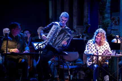 Peter und der Wolf: Bei "Peter und der Wolf von St. Pauli" dirigiert Omer Meir Wellber das Philharmonische Staatsorchester – greift aber auch mal selbst zum Akkordeon und spielt einen Hans-Albers-Schlager. Links von ihm sitzt der Autor Axel Brüggemann, der den Erzähler des Stückes spielt, rechts Carolin Spieß als Jutta Pinzner.