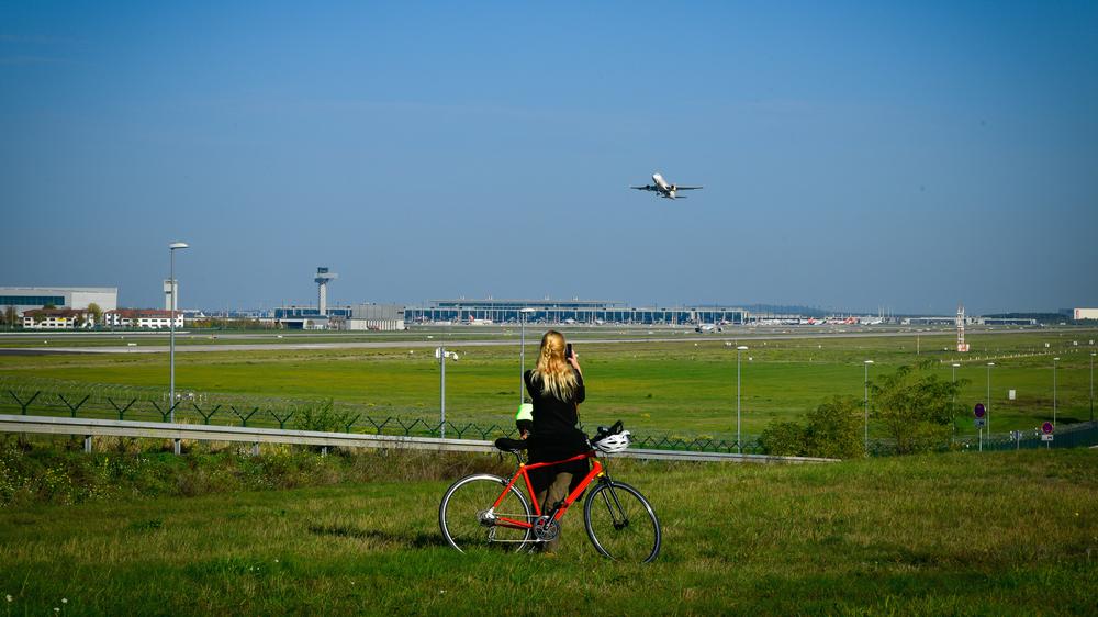 Flughafen BER: Flughafen BER Eine Frau steht am 30. Oktober 2022 mit ihrem Fahrrad am Flughafen-Rundweg bei Selchow in Brandenburg 