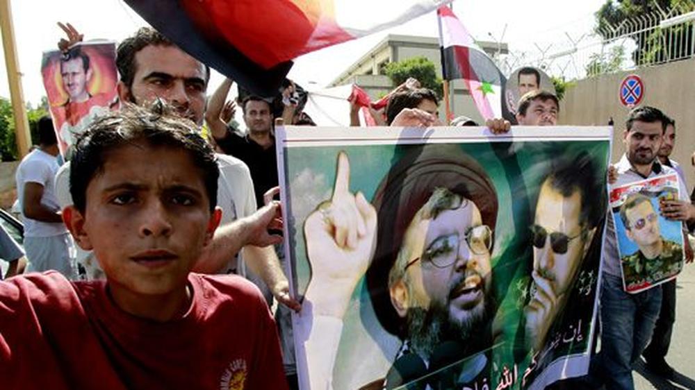 Hisbollah: Hisbollah-Anhänger mit einem Bild ihres Anführers Hassan Nassrallah (l.) und des syrischen Präsidenten Baschar al-Assad