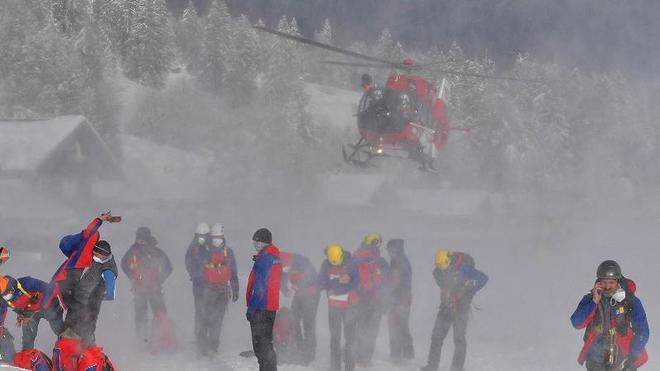 Zwei Lawinentote in Schweiz: Ein Helikopter landet hinter Helfern der Bergrettung.