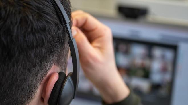 Datenverkehr: Ein junger Mann, der ein Headset trägt, nimmt an einer Videokonferenz teil.