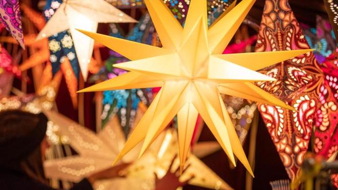 Kommunen: Bunte Weihnachtssterne werden an einem Stand auf dem Weihnachtsmarkt angeboten.