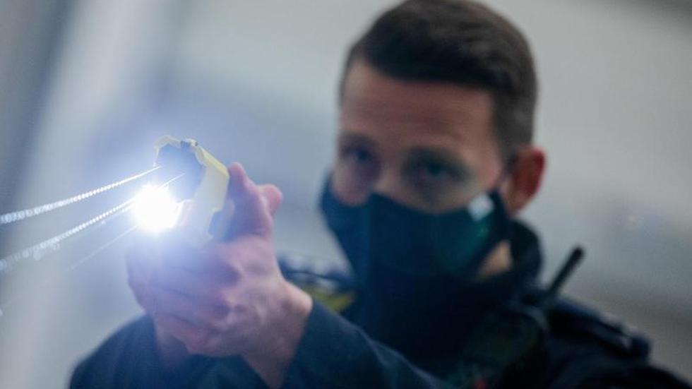 Polizei: Ein Polizeibeamter demonstriert einen Schuss mit einem Distanzelektroimpulsgerät (DEIG oder auch Taser).