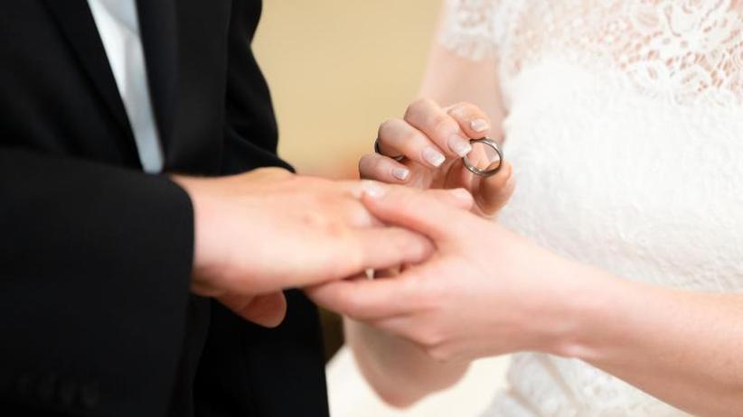 Gesellschaft: Ein Brautpaar steckt sich während ihrer Trauung die Ringe an.