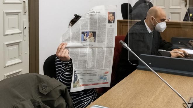 Prozess: Die Angeklagte verbirgt ihr Gesicht hinter einer Zeitung, neben ihr sitzt ihr Anwalt.