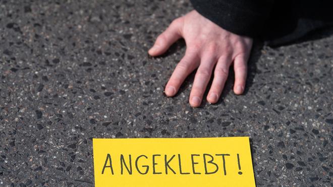 Dresden: Ein Demonstrant hat sich während eines Protests auf einer Straße festgeklebt.