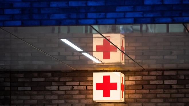 Krankenhäuser: Ein Leuchtkasten mit einem roten Kreuz hängt vor der Notaufnahme eines Krankenhauses.