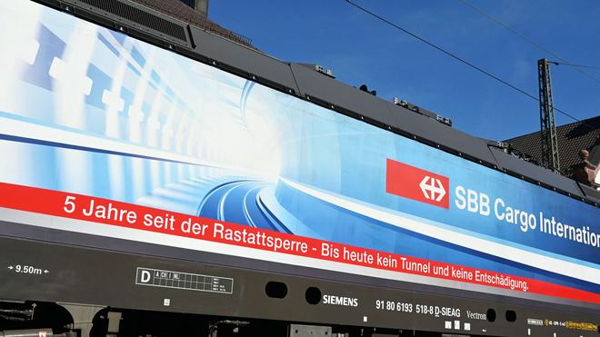 Rheintalbahn: «5 Jahre seit der Rastattsperre – Bis heute kein Tunnel und keine Entschädigung» steht auf einem Banner an einer Lok.