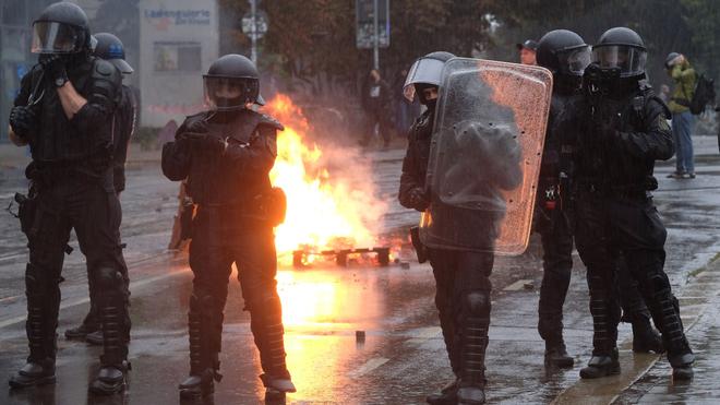 Innenministerium: Polizisten stehen bei einer Demonstration an einer brennenden Barrikade im Stadtteil Connewitz.