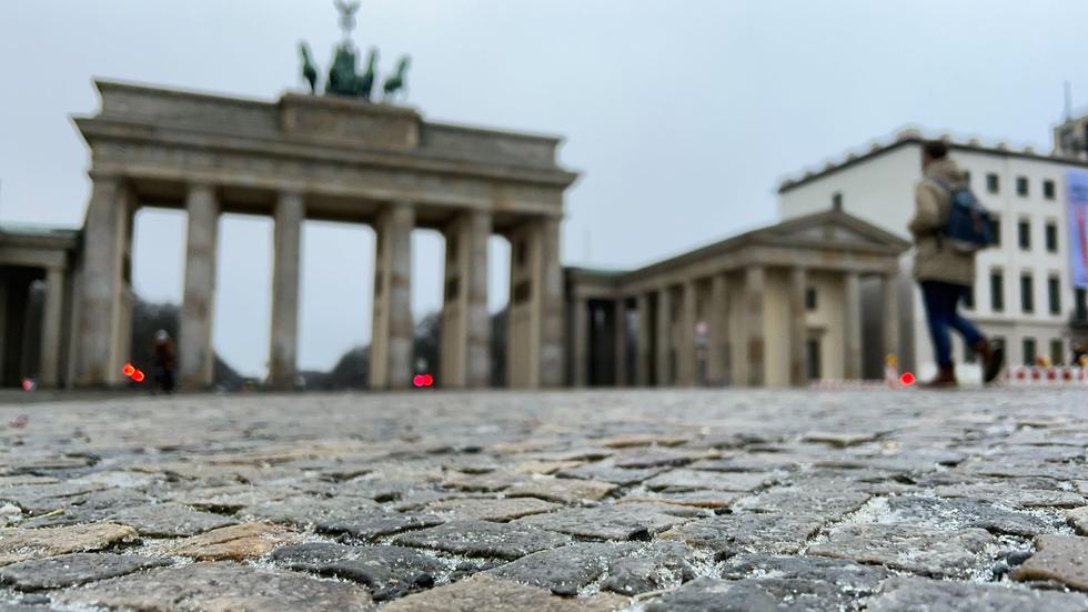 Charité in Berlin: Eine dünne Eisschicht liegt über den Pflastersteinen vor dem Brandenburger Tor.