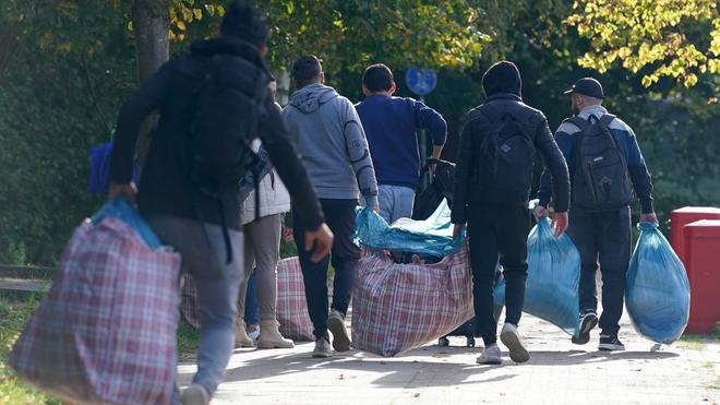 Schutzsuchende: Schutzsuchende aus Syrien gehen mit ihrem Gepäck zu einer Erstaufnahmeeinrichtung.