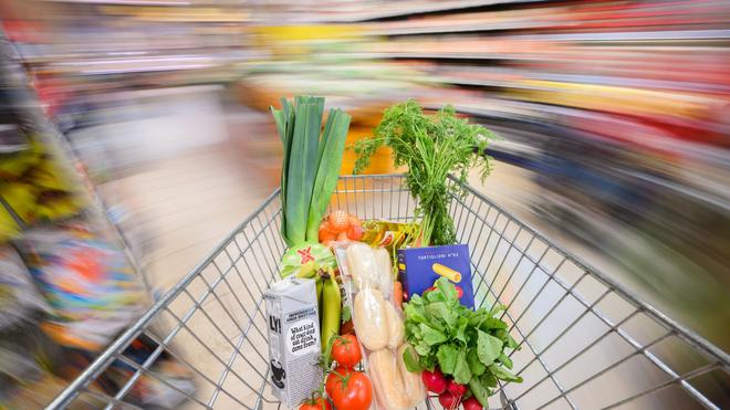 Einzelhandel: Ein mit Lebensmittel gefüllter Einkaufswagen wird durch einen Supermarkt geschoben.