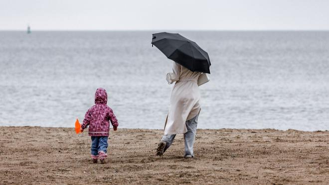 Wetter: Een vrouw met kinderen en een kind sinds ze elders naar het water op de Ostsee-Strand in Travemünde reizen.