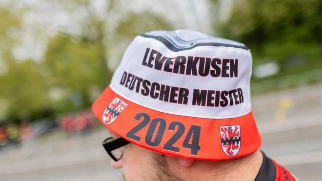 Bundesliga: Ein Fan trägt eine Mütze mit der Aufschrift „Leverkusen – Deutscher Meister 2024“ und einer stilisierten Meistertrophäe.