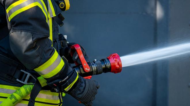 Saalekreis: Ein Mitglied der Feuerwehr versprüht Wasser aus einem Schlauch.