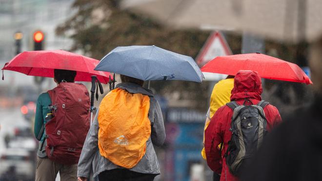 Wetter: Bei Regen schützen sich die Menschen mit ihren Regenschirmen.