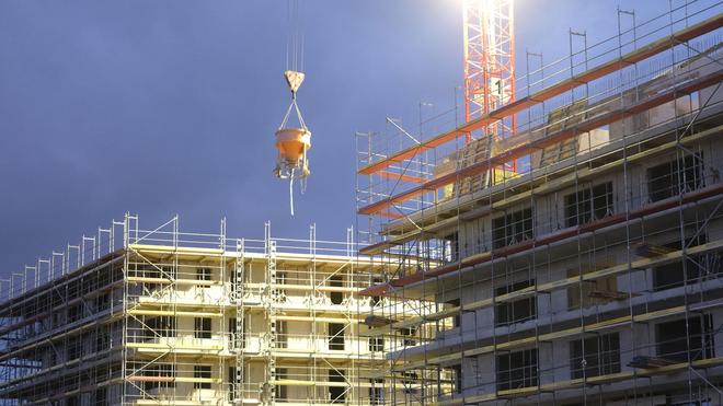 Wohnen: Rohbauten für Wohngebäude werden in der Abenddämmerung beleuchtet.