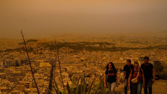 Wetter: Touristen spazieren auf dem Lycabettus-Hügel, während der Himmel über Athen mit dem antiken Akropolis-Hügel im Hintergrund infolge von Saharastaub eingetrübt ist.