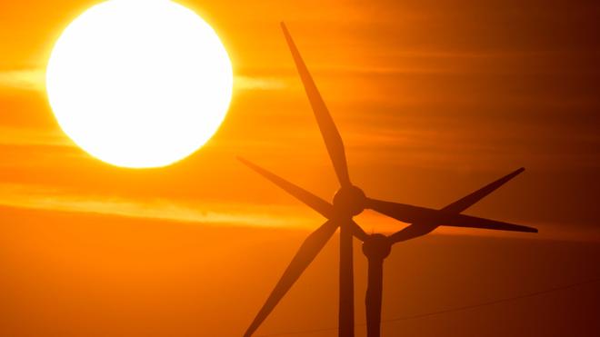 Energie: Die Sonne geht hinter Windrädern auf.