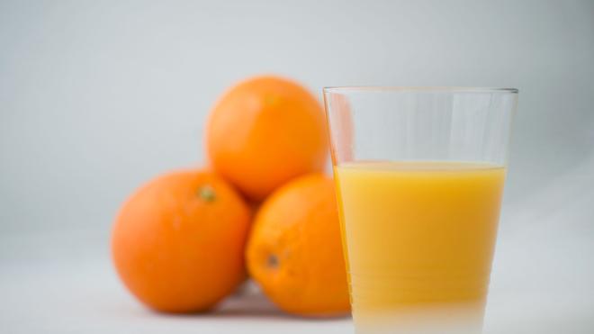 Lebensmittel: Orangen und ein Glas Orangensaft stehen auf einem Tisch.