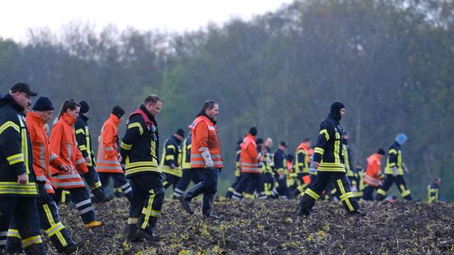 Familie: Feuerwehrleute laufen über einen Acker bei Bremervörde.