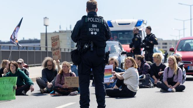 Demonstrationen: Ein Polizist beobachtet Klimaaktivisten auf der Dresdner Carolabrücke.