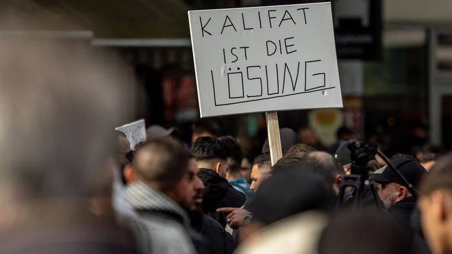 Extremismus: Teilnehmer einer Islamisten-Demo halten ein Plakat mit der Aufschrift „Kalifat ist die Lösung“ in die Höhe.