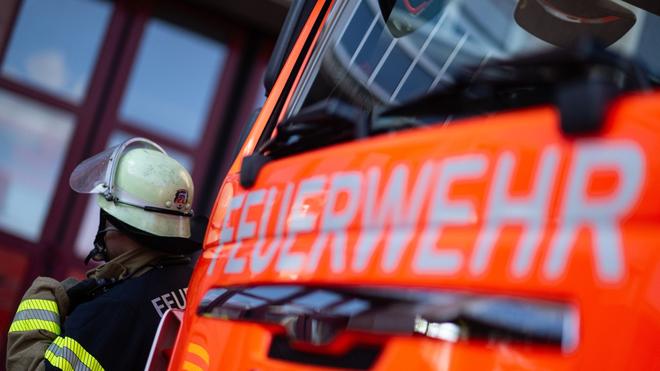 Berlin: Ein Feuerwehrmann steht neben einem Feuerwehrfahrzeug.