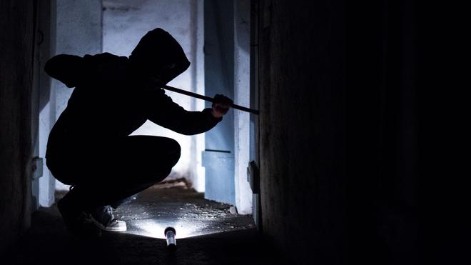 Erfurt : Ein Mann hebelt mit einem Brecheisen eine Tür im Keller eines Wohnhauses auf.