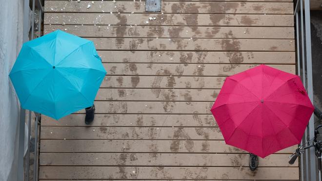DWD-Prognose: Passanten gehen unter Regenschirmen spazieren.