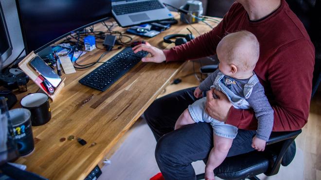 Statistik: Ein junger Vater im Home-Office mit seinem sechs Monate alten Sohn.