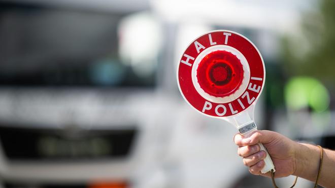 Verkehr: Ein Polizist hält während einer Verkehrskontrolle eine Polizeikelle in der Hand.