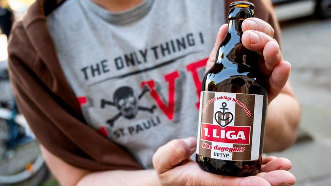 Fußball: Ein Fan hält eine Bierflasche mit der Aufschrift „1.Liga“ in der Hand.