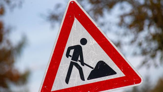 Verkehrsinformationszentrale: Ein zerkratztes Gefahrenschild am Arbeitsplatz mit dem Piktogramm eines Bauarbeiters.